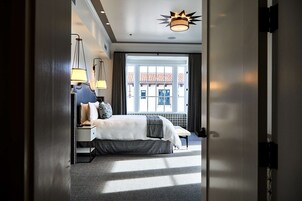 A hotel room with a bed, bedside lamps, a view of the outside, and a ceiling light fixture.