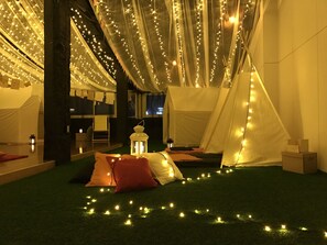 A tented area with string lights, a lantern, and pillows on artificial grass. - perBed Hostel (Yuchi)