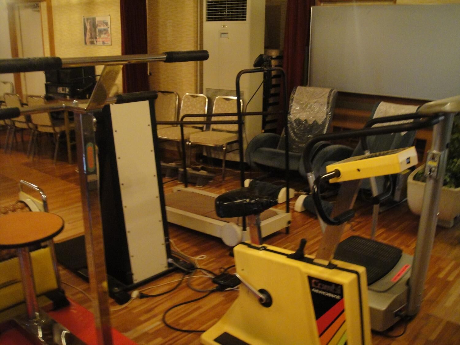 Un gimnasio con equipamiento de ejercicio que incluye cinta de correr, bicicleta estática y máquinas de pesas.