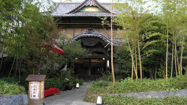 Un bâtiment japonais traditionnel, doté d’un toit recouvert de tuiles et d’une porte d’entrée en bois.