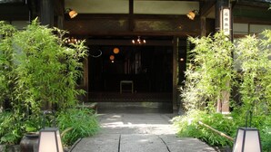 Une entrée de style japonais traditionnel, avec un chemin de pierres menant à une porte en bois.