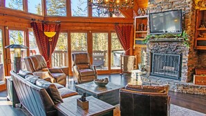 Una sala de estar acogedora con sofás de cuero, una chimenea de piedra y un televisor grande.