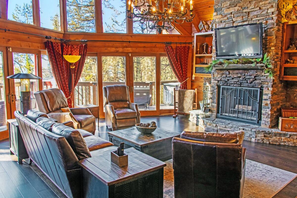 Una sala de estar acogedora con sofás de cuero, una chimenea de piedra y un televisor grande.