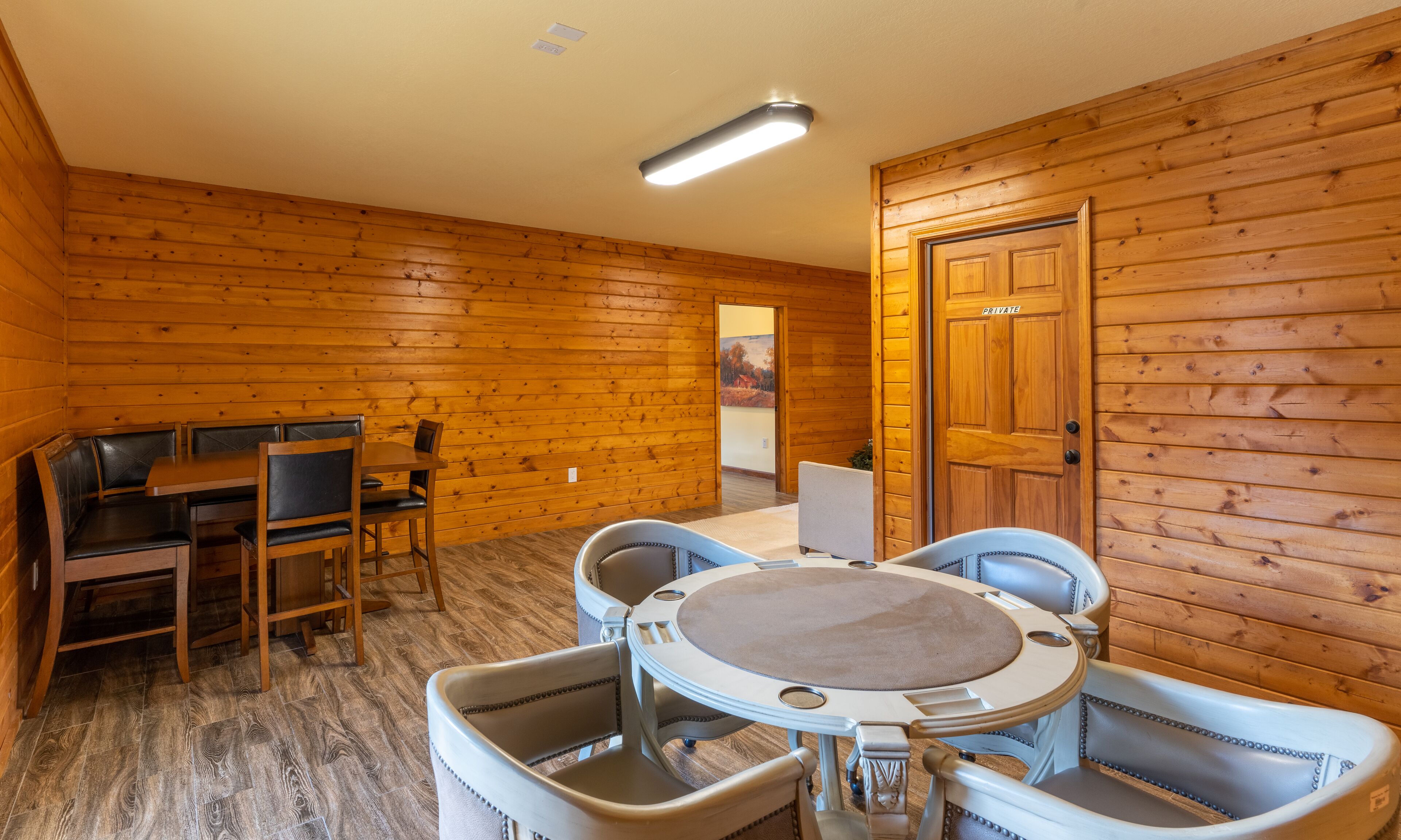 Ein Holzblockbau-Innenraum mit Esstisch und Stühlen, einer Privattür und einer Deckenleuchte.