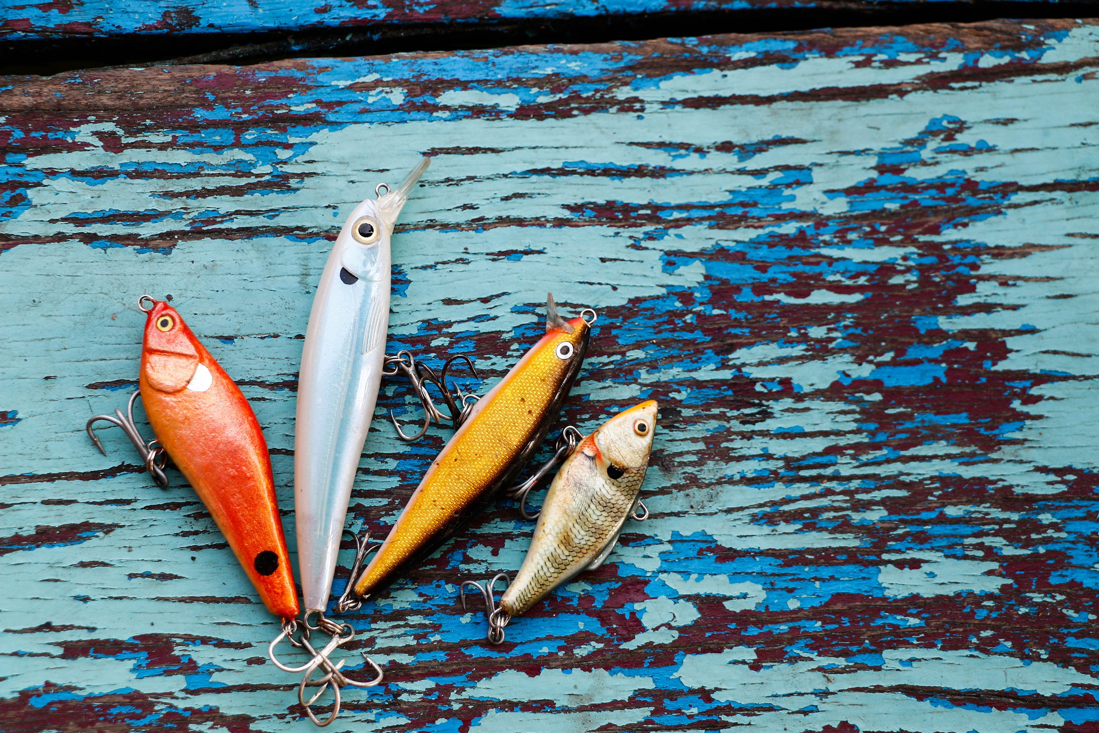 Four fishing lures on a weathered blue wooden surface.