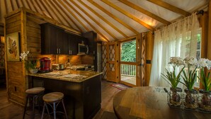 Interior acogedor de una cabaña con área de cocina, vigas de madera y una mesa de comedor.