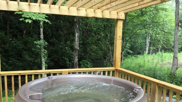 Un jacuzzi en una terraza de madera con vistas a una zona boscosa.