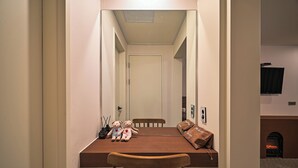 Un estrecho pasillo con una mesa de madera y sillas, un oso de peluche y una bolsa marrón.