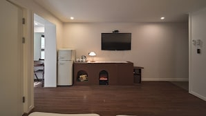 Una sala de estar con chimenea, un televisor de pantalla plana montado en la pared y un comedor visible a través de una puerta abierta.