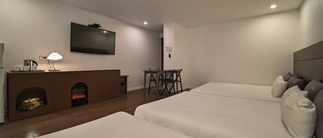 Habitación de hotel moderna con dos camas, una televisión de pantalla plana, chimenea, escritorio y lámpara.