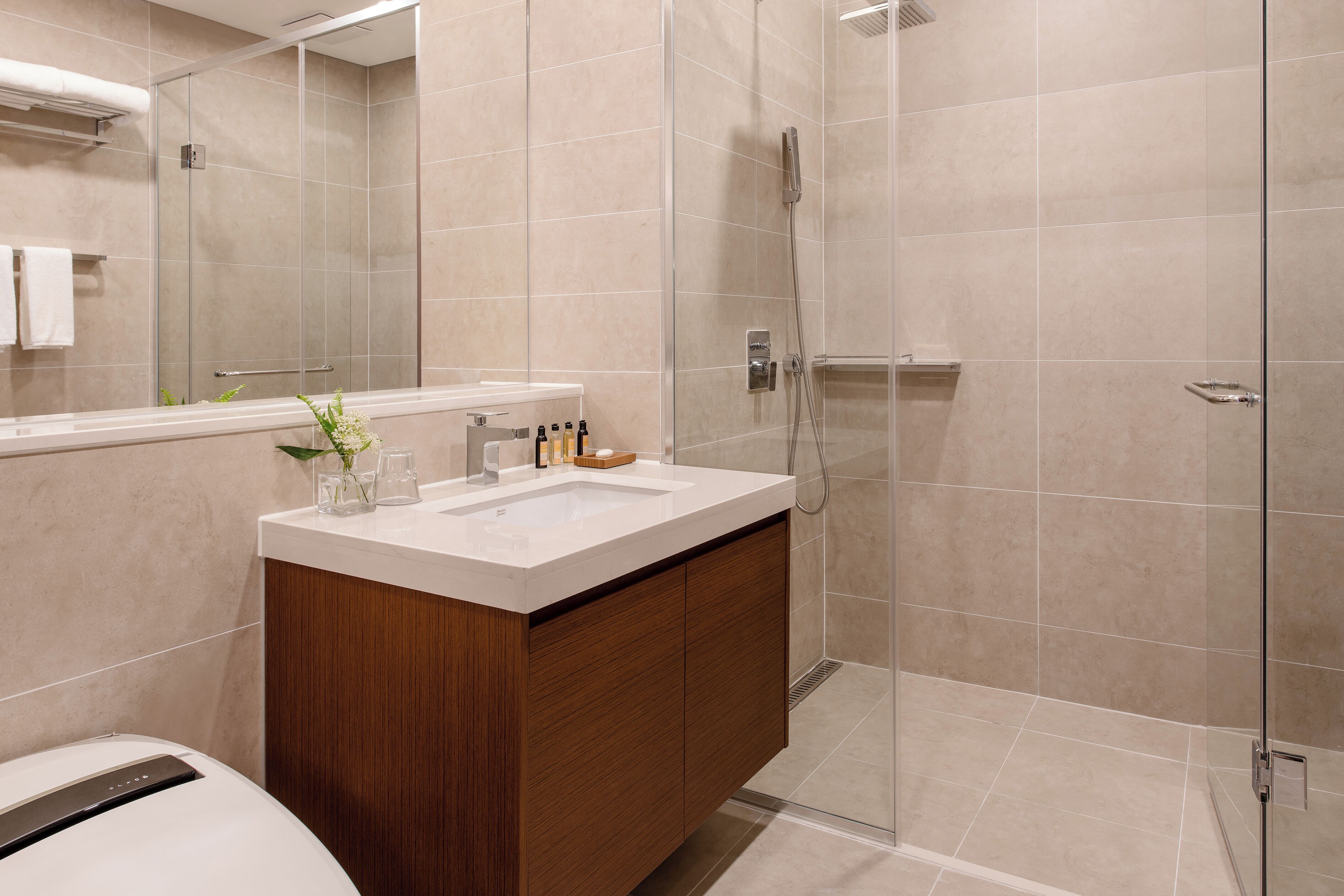 A modern bathroom with a glass-enclosed shower, a wooden vanity, and a large mirror.