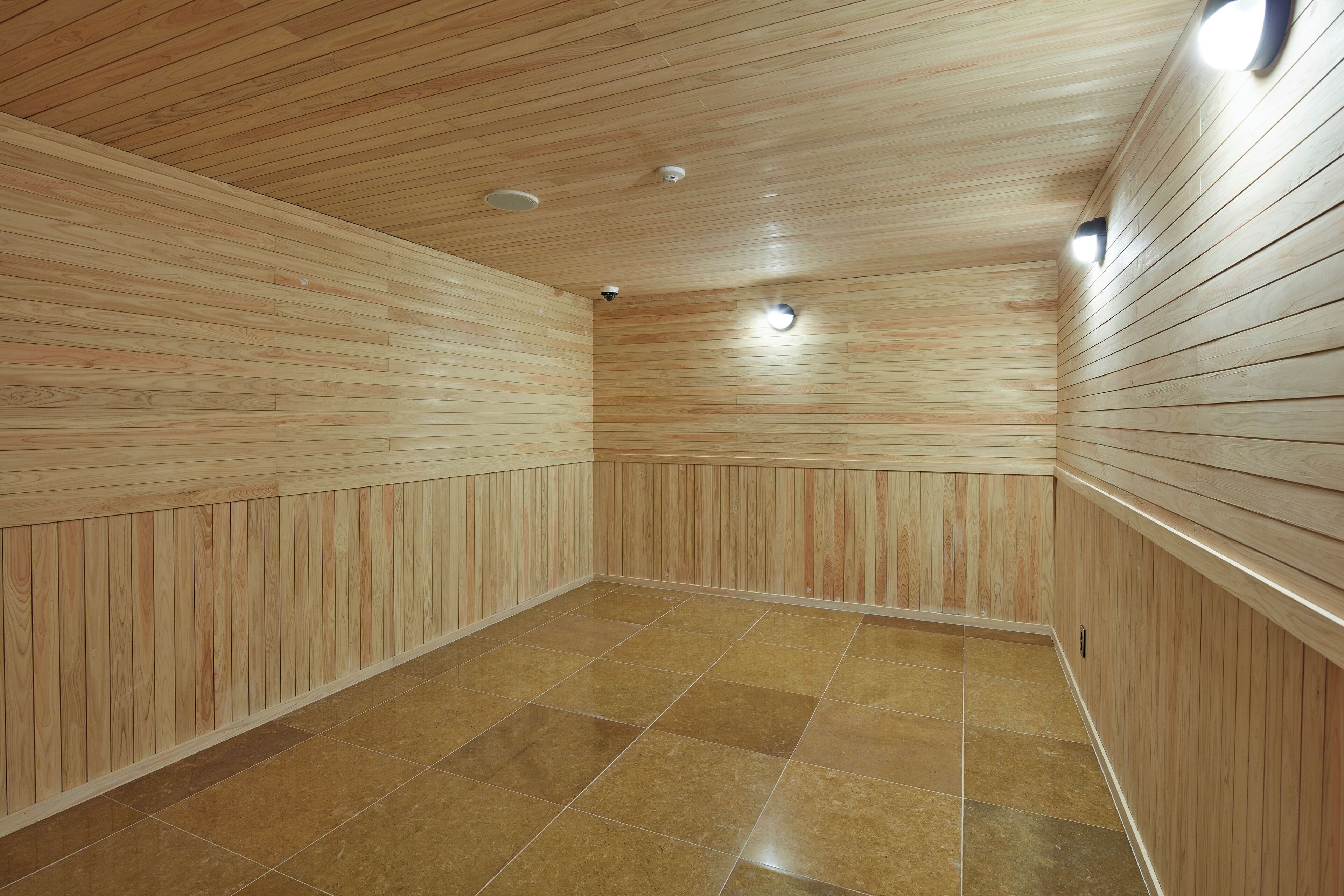 Un sauna avec des panneaux de bois aux murs et un sol carrelé.