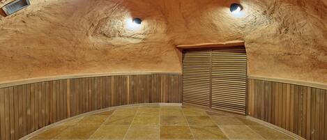 A curved ceiling with recessed lighting, a wooden panel wall, and a tiled floor.
