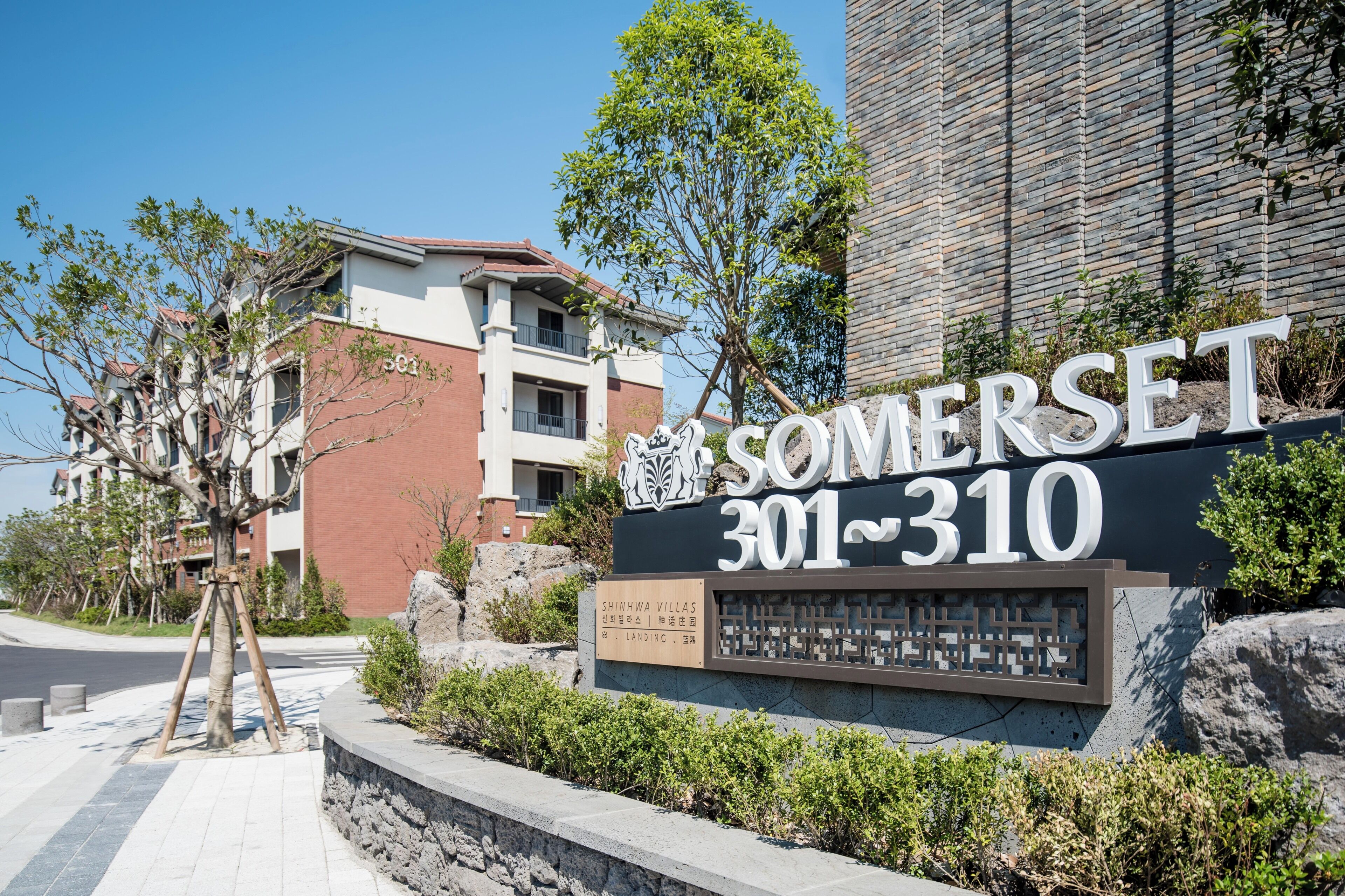 A sign for SOMERSET 301-310, a building with a brick facade, and a tree in the foreground.