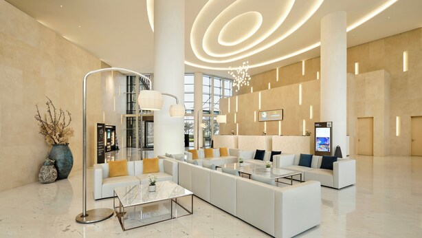 Un vestíbulo moderno con una amplia recepción, un sofá blanco grande y una mesa de centro de vidrio.