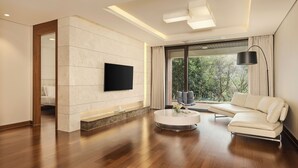 Una sala de estar moderna con un televisor de pantalla plana, un sofá, una mesa de centro y un amplio ventanal con cortinas.