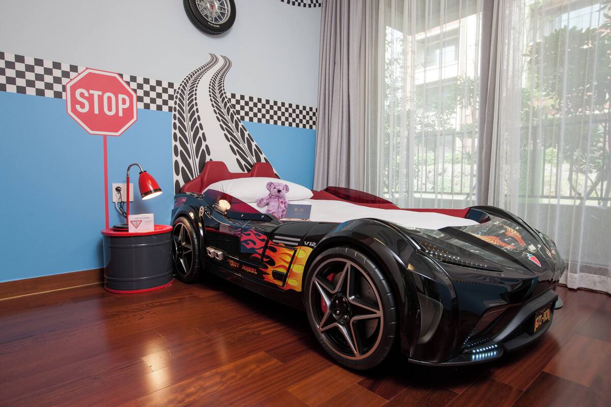 Een kamer met een groot model van een sportauto, een stopbord en een muurdecoratie met een race thema.