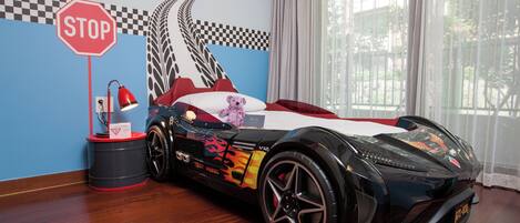 Ein Zimmer mit einem großen Modell eines Sportwagens, einem Stoppschild und einer Rennsport-Motiv-Wandgestaltung.