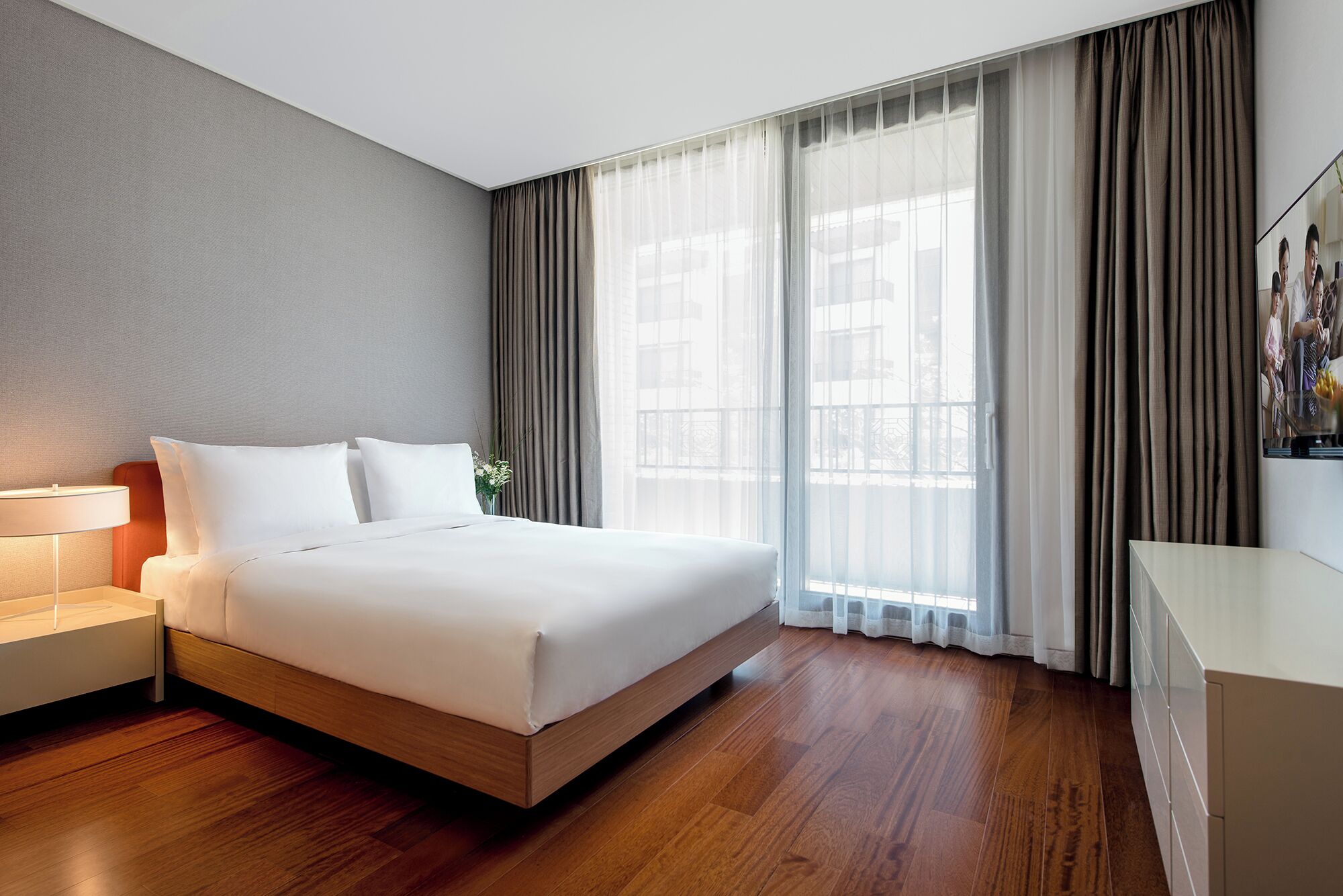 Een moderne hotelkamer met een groot bed, een nachtkastje, een bureau en een raam met gordijnen.