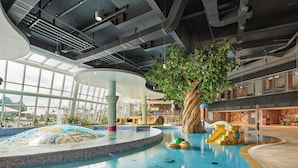 Un área de piscina interior con un árbol central, una fuente de agua y una zona de estar.