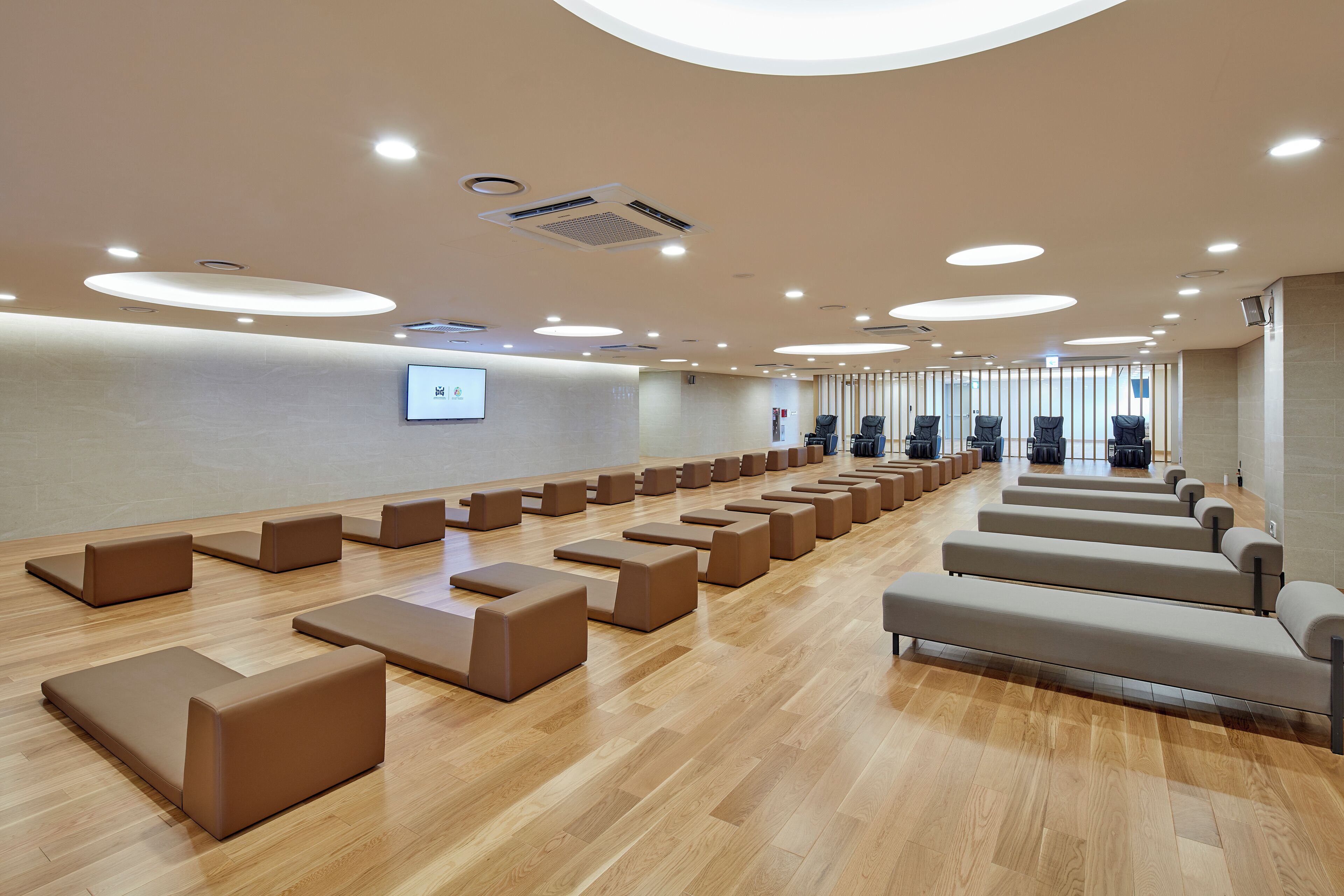 Un salón de conferencias con filas de asientos, una pantalla de proyector y suelo de madera.