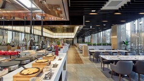Un restaurante moderno con una barra alargada, varias mesas y un pasillo central.