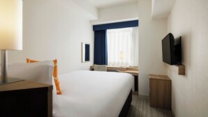 A hotel room with a large bed, a desk, a chair, a TV, and a window with curtains. - Four Points Flex by Sheraton Kanazawa (Kanazawa)