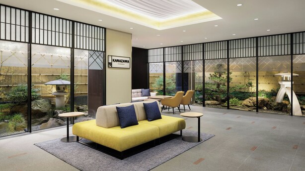 A modern hotel lobby with a yellow sofa, seating area, and a view of a garden through large windows. - Four Points Flex by Sheraton Kanazawa (Kanazawa)