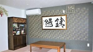 Una habitación con un armario de madera, una mesa y una pared con un diseño de cuadros y una obra de caligrafía enmarcada.
