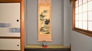 Una habitación tradicional japonesa con suelo de tatami, pantalla shoji y un pergamino colgante.
