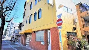 Un edificio amarillo con un letrero de ‘prohibido el paso’, una puerta y una ventana con una reja de metal.