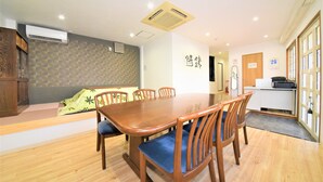 Un comedor con una mesa y sillas de madera, un banco empotrado y una cocina con mostrador y armarios.