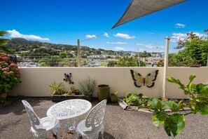 A patio with a table and chairs, surrounded by potted plants and a butterfly decoration. - Parkhill Fine Accommodation (Whangarei)