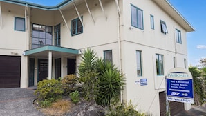 A two-story building with a sign indicating it is a luxury accommodation offering en-suite rooms, breakfast, and a private deck.
