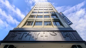 Een hoog gebouw met een opvallend ‘STAY’-bord aan de bovenkant.