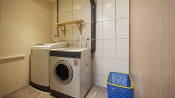 A laundry room with two washing machines and a blue laundry basket.