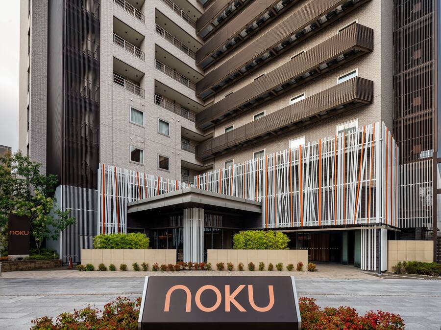 A modern building with a prominent 'noku' sign, featuring a multi-story structure with balconies and a central entrance.