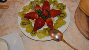 Un plat de fruita tallada disposada en cercle, amb una cullera al costat.