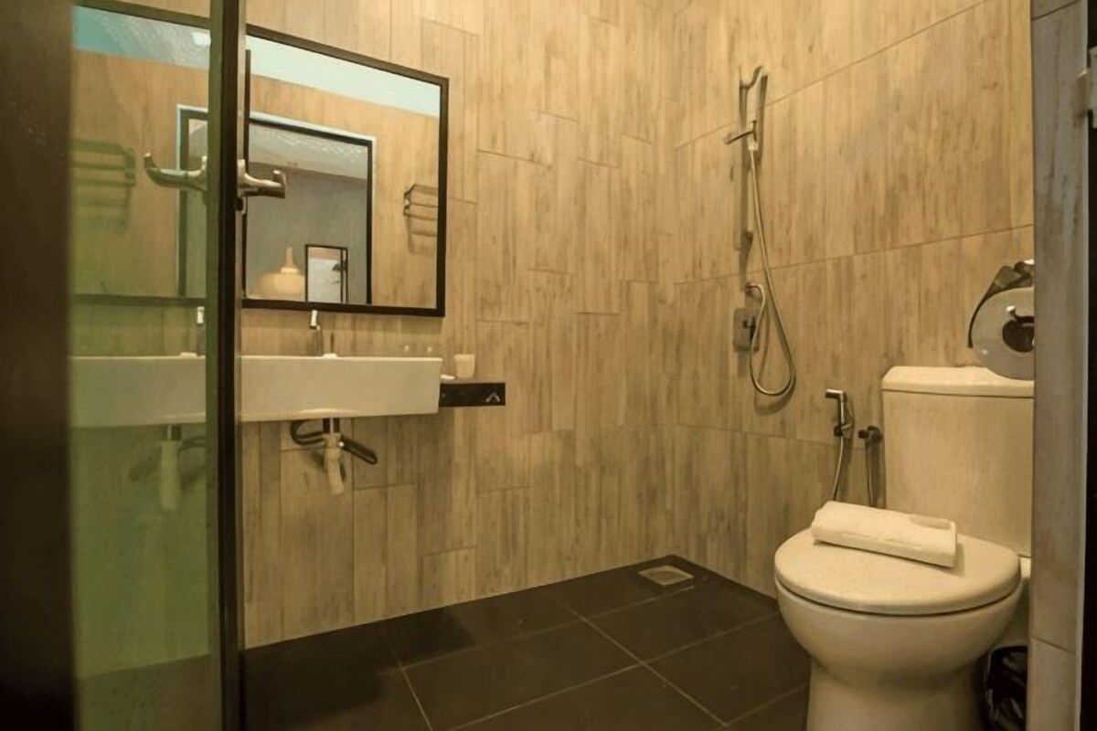 A bathroom with a sink, mirror, toilet, and shower.