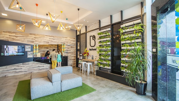 Un moderno vestíbulo de hotel con mostrador de recepción, zona de estar y pared vertical cubierta de jardín.
