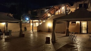 An outdoor courtyard with a staircase leading to a second-floor balcony. There are tables and chairs set up for dining, and a few potted plants are visible. - Sleep and go Hotel (Fiumicino)