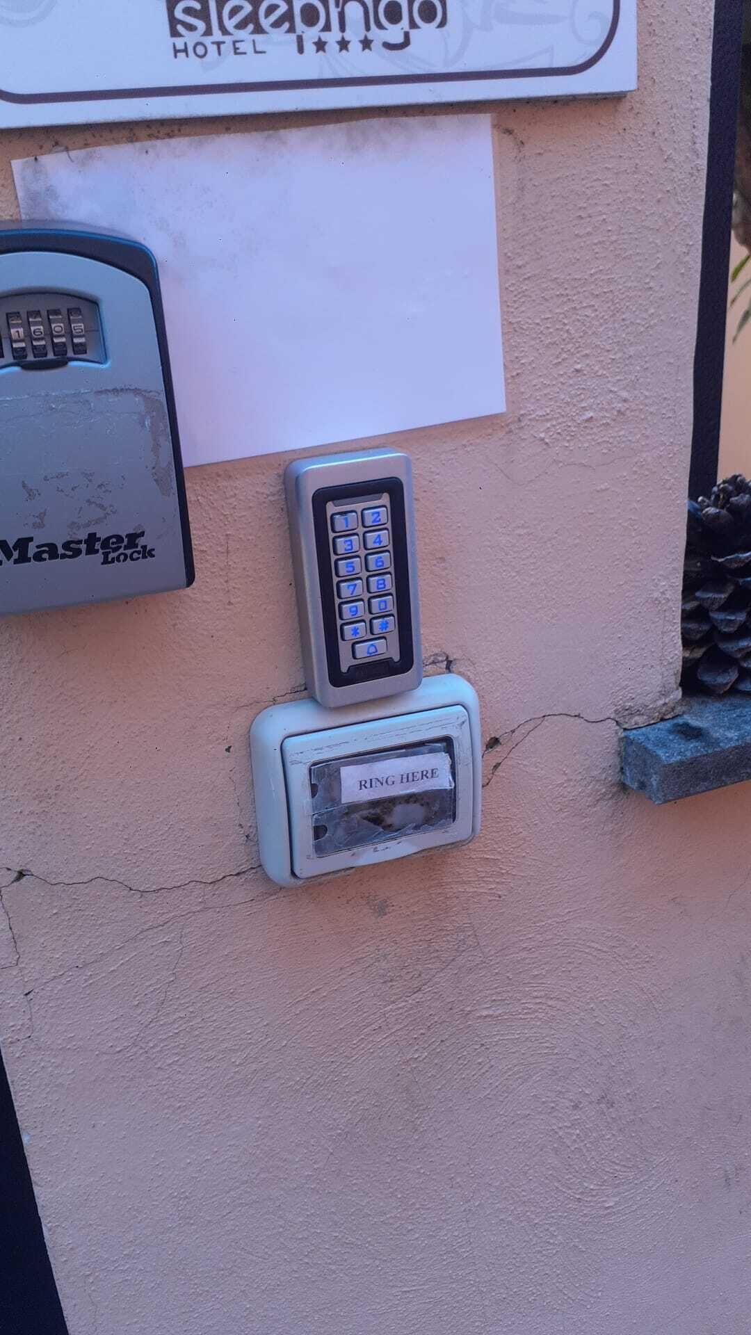 Een hotelingang met een keypad-slot en een bord erboven.