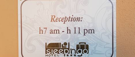 A reception sign for Sleepygo Hotel with operating hours from 7 am to 11 pm.