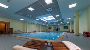 Una piscina con sillas de descanso y suelo de baldosas.