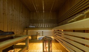 A sauna with wooden benches, a bench with a towel, and a candle on the floor. - Hotel Europa (Belvedere Marittimo)