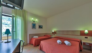 Une chambre d’hôtel avec deux lits, un bureau, une chaise et une fenêtre avec des rideaux.