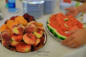 Une table avec une assiette de pêches et une pastèque.