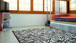 Una habitación con una cama litera, un tapete estampado de cebra, un televisor y una ventana con persianas.