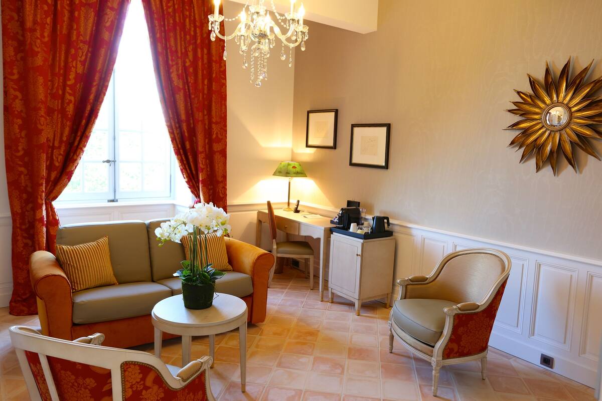 Un salon comprenant un canapé, un fauteuil, une table basse et un bureau avec une lampe.