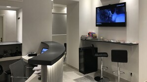 Zona de bar moderna con una pantalla plana que muestra una película de moda, una barra y taburetes de bar.